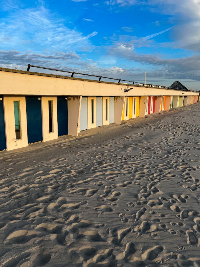 Vibrant beach huts line the sandy shore under a clear blue sky in Hauts-de-France.